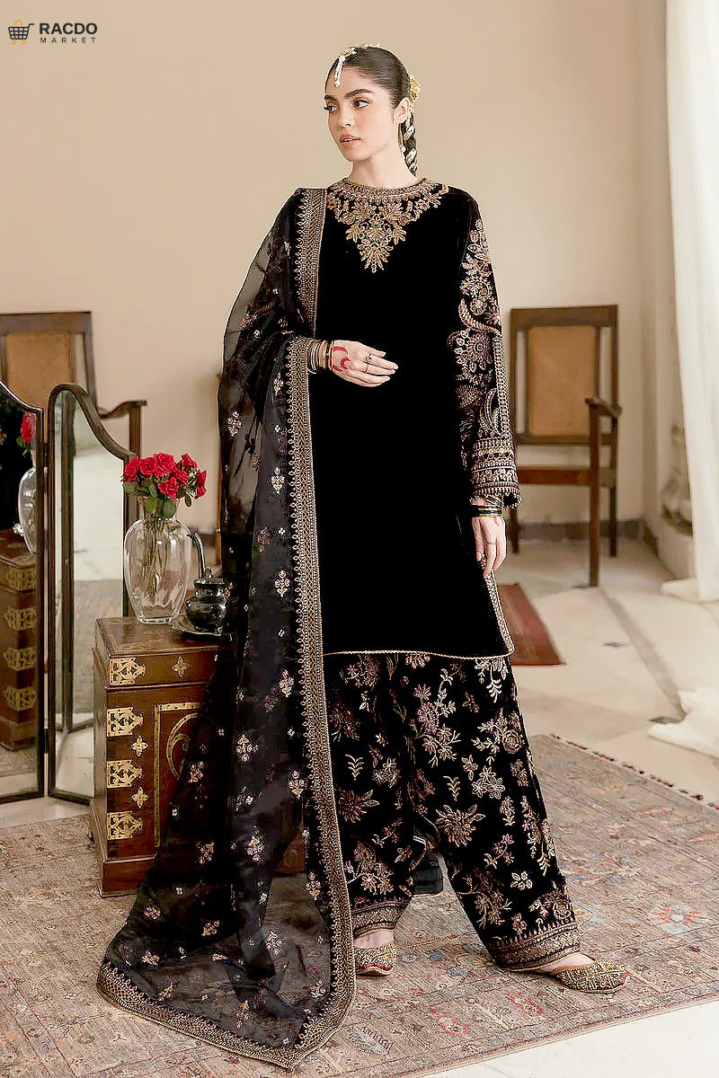Woman in black embroidered traditional outfit with dupatta in a room setting

