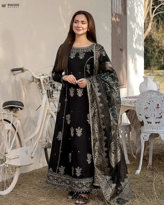 Woman in a black embroidered traditional outfit standing next to a white bicycle outdoors.

