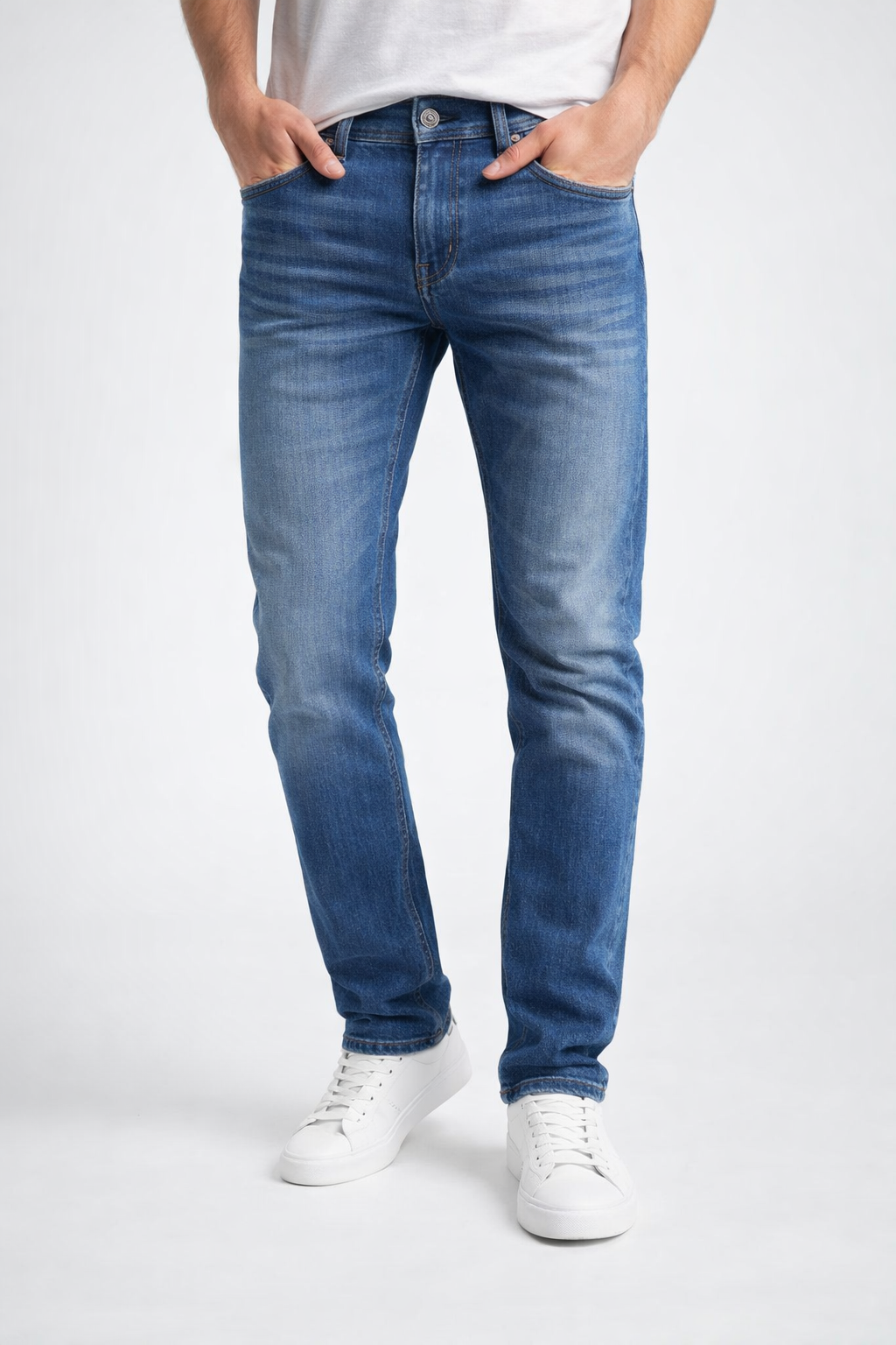 Person wearing blue jeans and white sneakers on a white background

