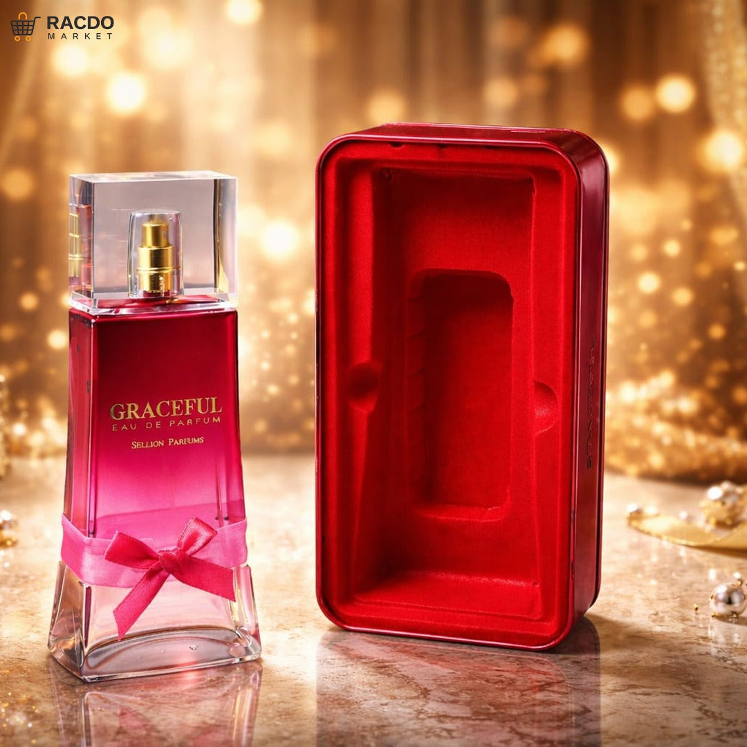 Red perfume bottle with a bow and red packaging box on a reflective surface with blurred lights in the background.