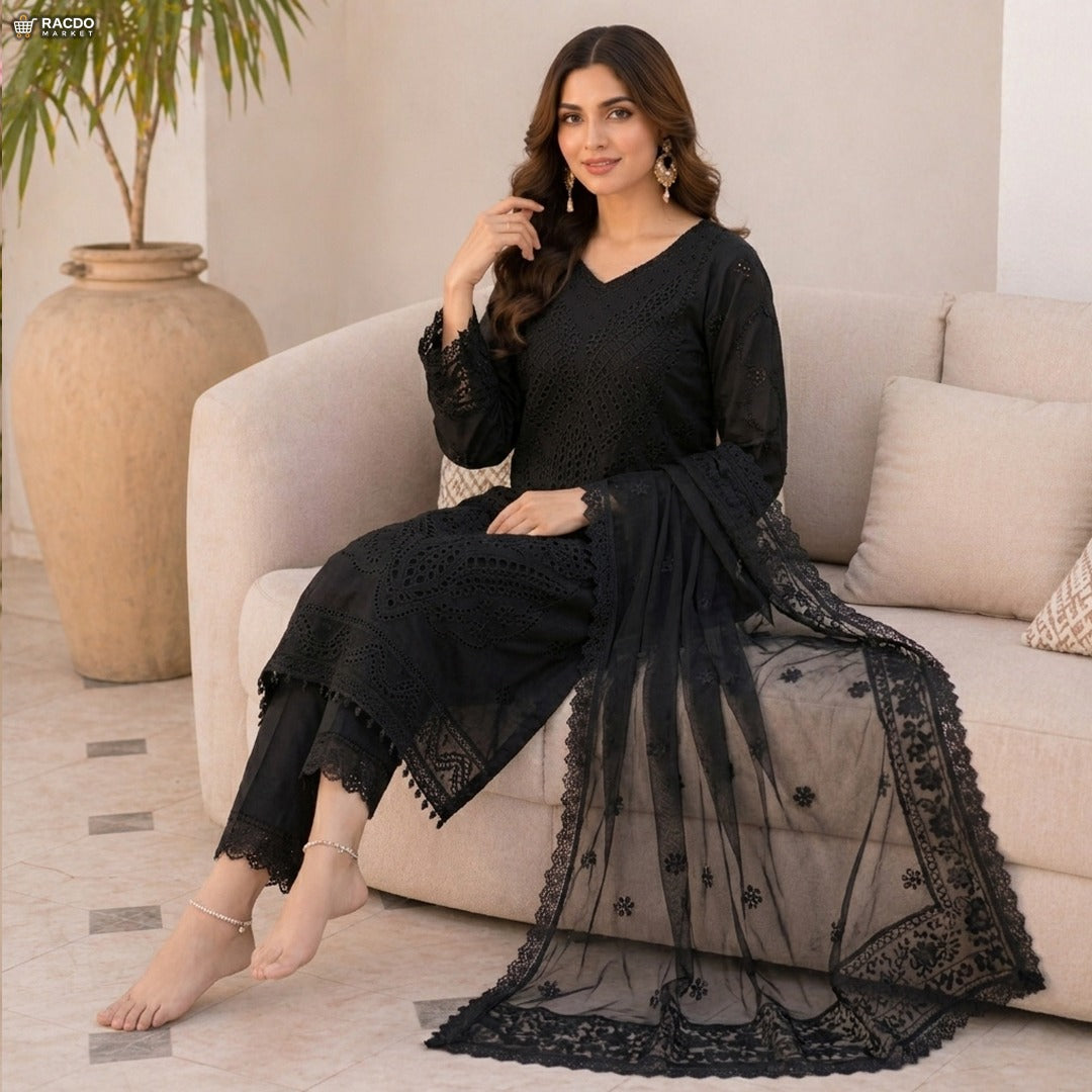 Woman in a black traditional outfit sitting on a beige sofa with a plant in the background

